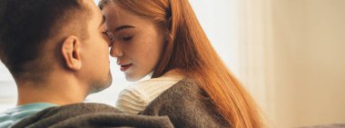 Çilli kızıl saçlı kadın kanepesinde sevgilisiyle oturuyor ve birlikte iyi vakit geçiriyor.