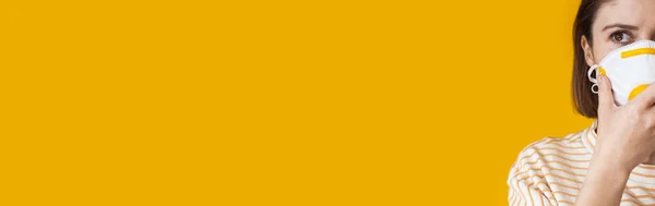 Preoccupata donna caucasica indossa una maschera protettiva e posa su una parete gialla con spazio libero — Foto Stock