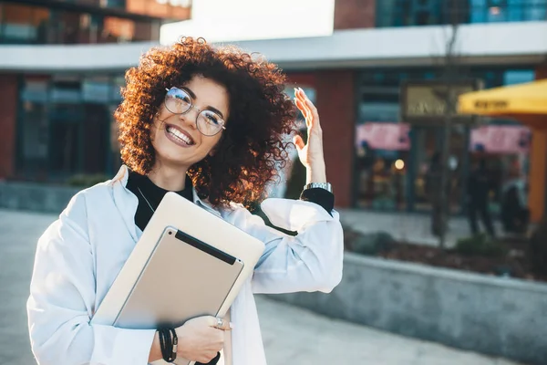 Curly cabelo empresário posando fora em óculos com alguns gadgets modernos está sorrindo para a câmera — Fotografia de Stock