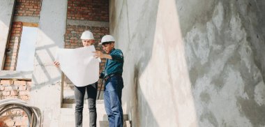 Kasklı iki Kafkas mühendisi yeni apartman planına bakıyor.