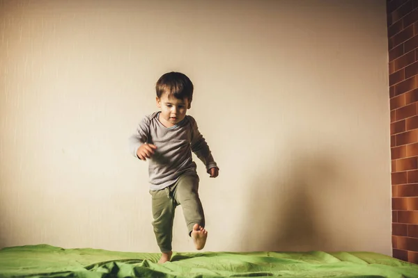 Garçon caucasien sauter sur le canapé vert et jouer dans la chambre — Photo