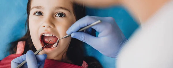Jong meisje met een examen bij de tandarts is op zoek naar hem werken met behulp van speciaal gereedschap — Stockfoto