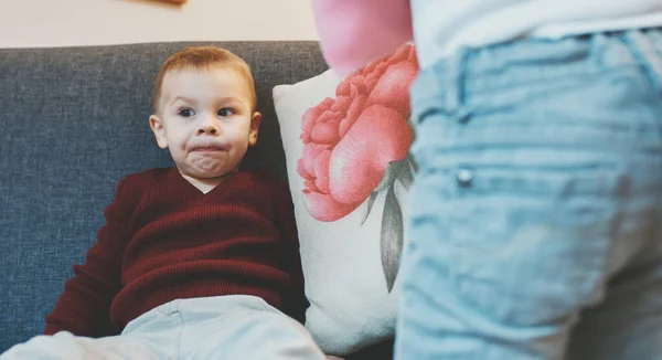 Caucásica madre explicando algo a su pequeño hijo mientras está sentado en el sofá y pensando —  Fotos de Stock