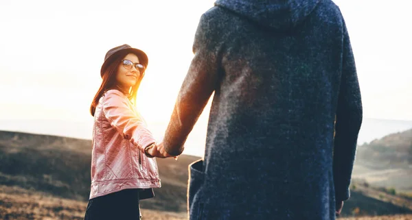 Belle femme avec des lunettes et un chapeau tenant la main de son amant et posant dans un champ — Photo