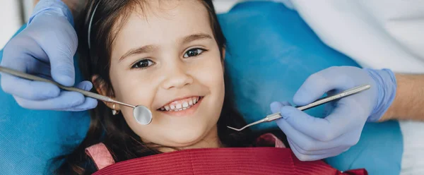 Close-up portret van een Kaukasisch meisje het hebben van een examen bij de pediatrische tandarts terwijl glimlachen op camera — Stockfoto