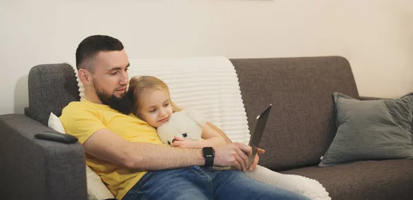 아버지 어깨에 누워 태블릿을 보면서 곰 인형을 안고 있는 사랑 스러운 소녀 — 스톡 사진