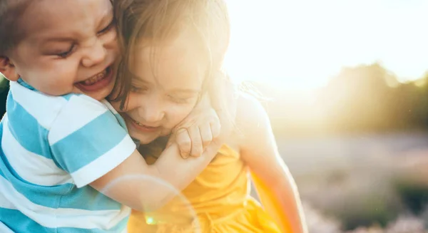 Κοντινό πορτραίτο ενός καυκάσιου αγοριού που αγκαλιάζει την αδερφή του ενώ παίζουν μαζί έξω. — Φωτογραφία Αρχείου