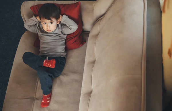 Retrato de vista superior de un niño caucásico aislado en casa durante la cuarentena acostado en el sofá —  Fotos de Stock