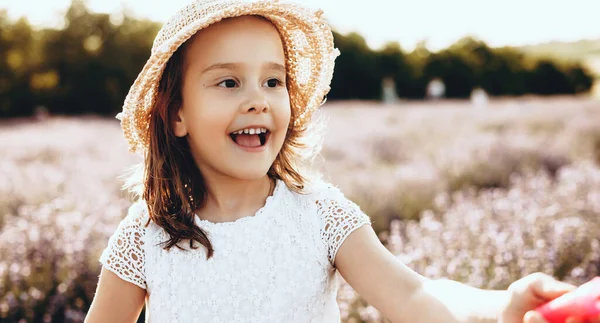 Menina encantadora com chapéu andando e sorrindo em um campo de lavanda em um dia ensolarado — Fotografia de Stock