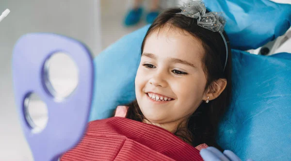 Gelukkig klein meisje glimlachen in de spiegel na een operatie bij de tandarts — Stockfoto