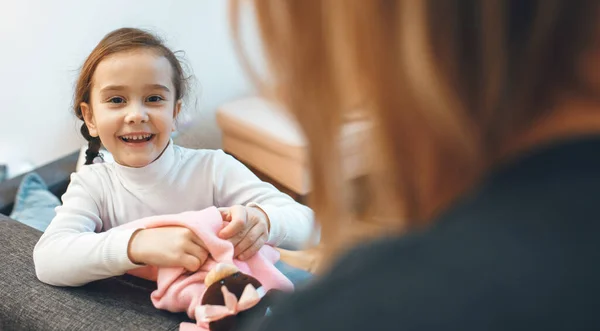 Menina feliz e sua mãe brincando com um urso de pelúcia na sala de estar — Fotografia de Stock