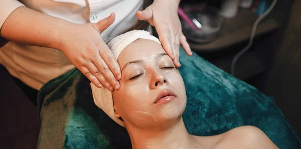Zabieg masażu twarzy wykonywany w centrum spa dla młodej białej kobiety z zamkniętymi oczami — Zdjęcie stockowe