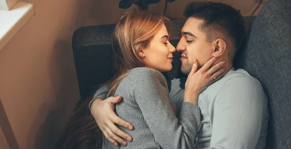 Vue supérieure de l'homme caucasien couché sur le canapé et embrassant sa femme aux cheveux roux avec des taches de rousseur — Photo