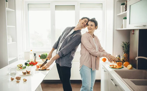 L'uomo caucasico e sua moglie preparano il cibo in cucina sorridono e si divertono insieme — Foto Stock