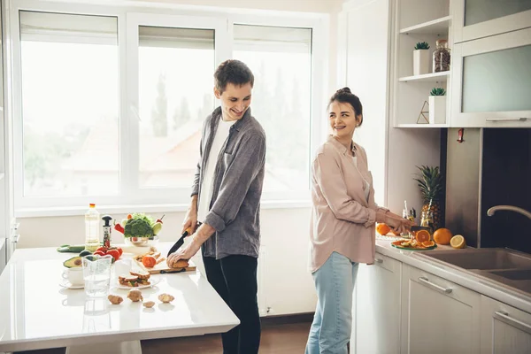 Szép kaukázusi kupé mosolyognak egymásra, miközben ételt készítenek együtt a konyhában. — Stock Fotó
