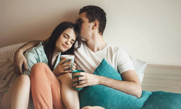 Happy caucasian couple in bed drinking tea in the morning while embracing and enjoying time — Stock Photo, Image