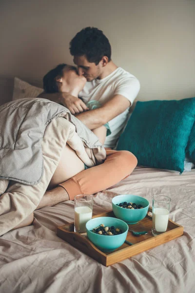 Caucasian couple kissing and embracing in bed before eating cereals with milk — Stock Photo, Image