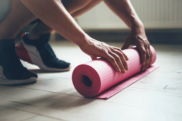 Homem caucasiano terminando de fazer exercícios está reunindo seu tapete de ioga do chão — Fotografia de Stock