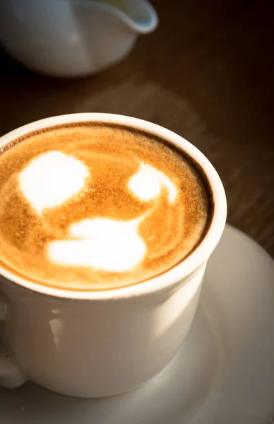 Uma xícara de café com espuma de leite dos namorados na placa branca e — Fotografia de Stock