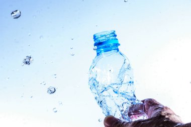 Beyaz arkaplanda su sıçratarak açılan şişe.