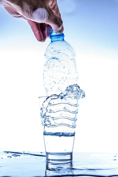 Empty bottle in glass of water with splashing and reflection. — Stock Photo, Image