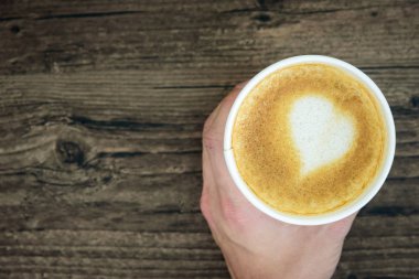 Latte Kahve sanat kalp sütlü kahverengi üzerine izole tutan bir adam