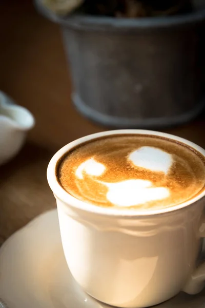 Una taza de café con espuma de leche de San Valentín en el plato blanco y — Foto de Stock