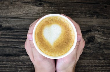 Latte Kahve sanat kalp sütlü kahverengi üzerine izole tutan bir adam