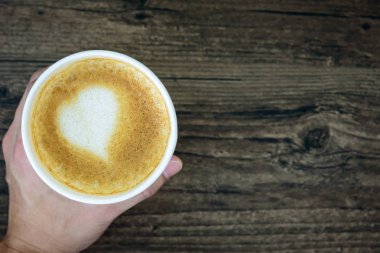 Latte Kahve sanat kalp sütlü kahverengi üzerine izole tutan bir adam