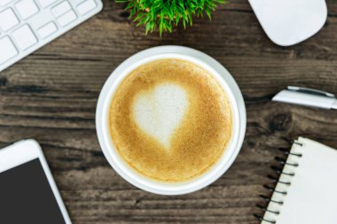 Bir latte kahve sanat kalp sütlü kahverengi ahşap Resepsiyon masasında 