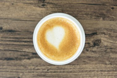 Bir latte kahve sanat kalp sütlü kahverengi ahşap masa üzerinde izole 