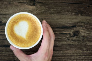Latte Kahve sanat kalp sütlü kahverengi üzerine izole tutan bir adam