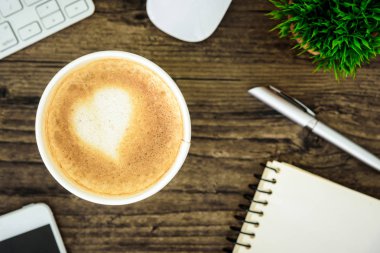 Bir latte kahve sanat kalp sütlü kahverengi ahşap Resepsiyon masasında 