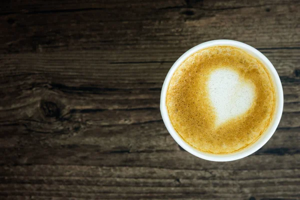 Un café con leche con leche de corazón de arte aislado en la mesa de madera marrón — Foto de Stock