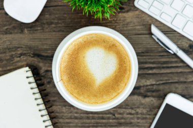 Bir latte kahve sanat kalp sütlü kahverengi ahşap Resepsiyon masasında 