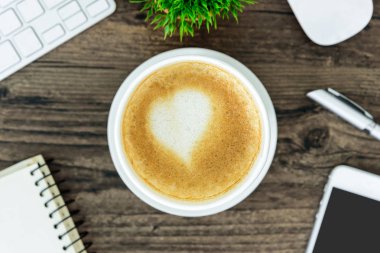Bir latte kahve sanat kalp sütlü kahverengi ahşap Resepsiyon masasında 
