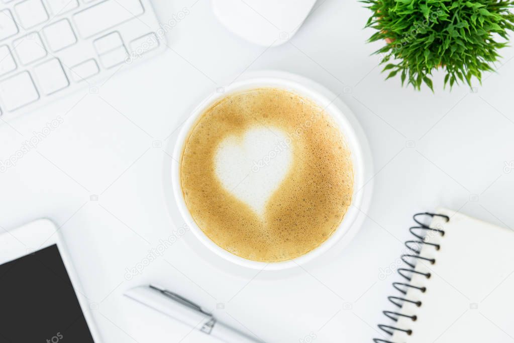 A latte coffee with art heart milk on the white desk table from 