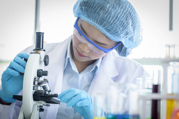 Asian yound student scientist researching with a microscope in a