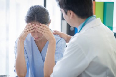 Bir doktor, üzgün ve unh ile hasta bir kadına bakar.