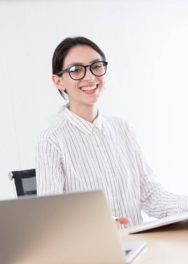 Ofiste gülümseyen ve mutlu bir şekilde çalışan gözlüklü bir iş kadını..