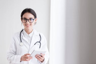 Bir doktor kadın, hastanedeki tablete gülümseyerek ve mutlulukla dokunmak zorundadır..