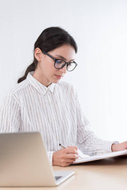 Ofiste gülümseyen ve mutlu bir şekilde çalışan gözlüklü bir iş kadını..