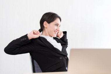 Bir iş kadını gülümseme ve mutlulukla ofis sandalyesine uzanıp dinleniyor..