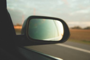 Yan yan ayna arka görüş mavi araba günbatımı üzerinde yol yansıma parçası 