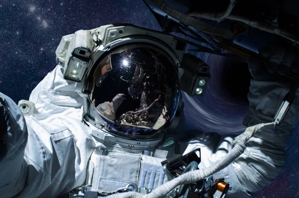 Uzayda bir yerlerde kara deliğin önünde bir astronot.