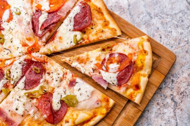 Ev yapımı pizza. Biberli ve peynirli. Masanın üzerinde ahşap kesim tahtası var.