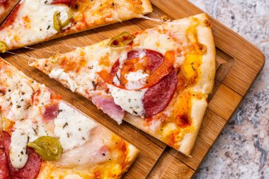 Ahşap kesim tahtasında pepperonili ve peynirli dilimlenmiş pizza. Seçici odak