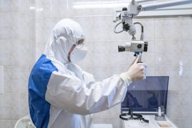 Koruyucu giysili doktor salgın döneminde tıbbi ekipmanlarla hastayı kontrol ediyor. Stereomikroskopi. Salgın hastalık konsepti. Seçici odak.