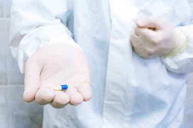 Doktorların elinde eldivenli mavi ve beyaz hap. Hastalık tedavisi konsepti, seçici odaklanma.