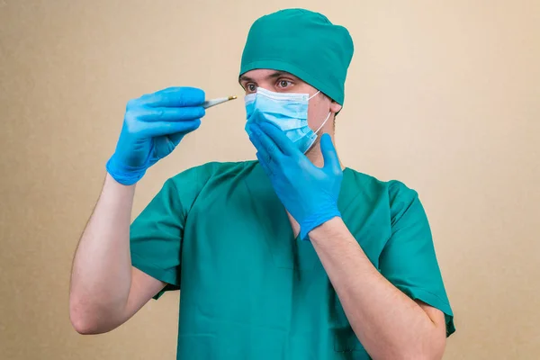Doctor Sorprendido Traje Verde Máscara Azul Guantes Con Termómetro Mano —  Fotos de Stock